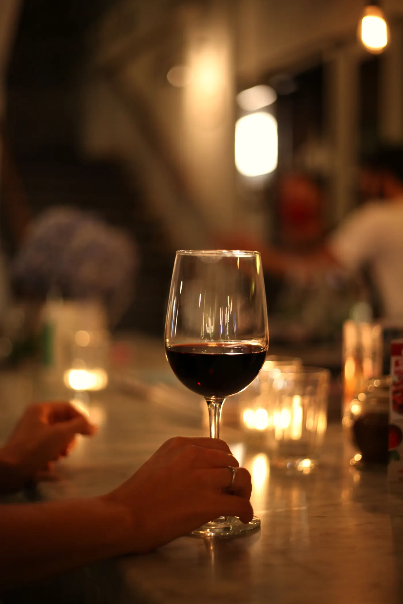 Een glas rode wijn aan de bar, bij kaarslicht